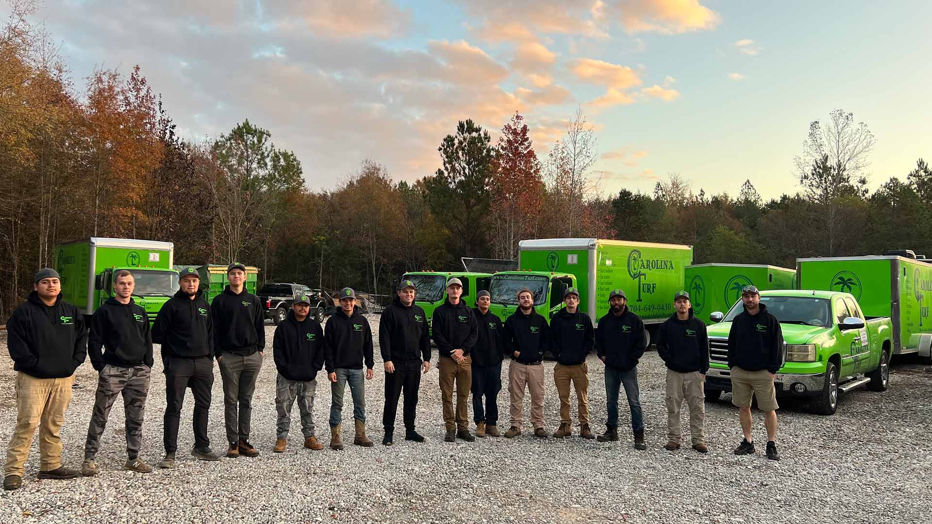 Carolina Turf expert team with company trucks in the background at sunset near Matthews, NC.