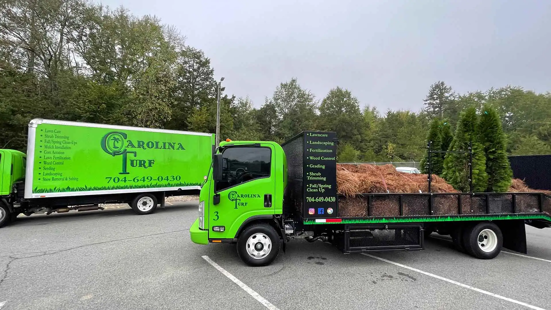 Two Carolina Turf Lawn and Landscape work trucks at a school with landscaping materials in Matthews, NC and surrounding areas.