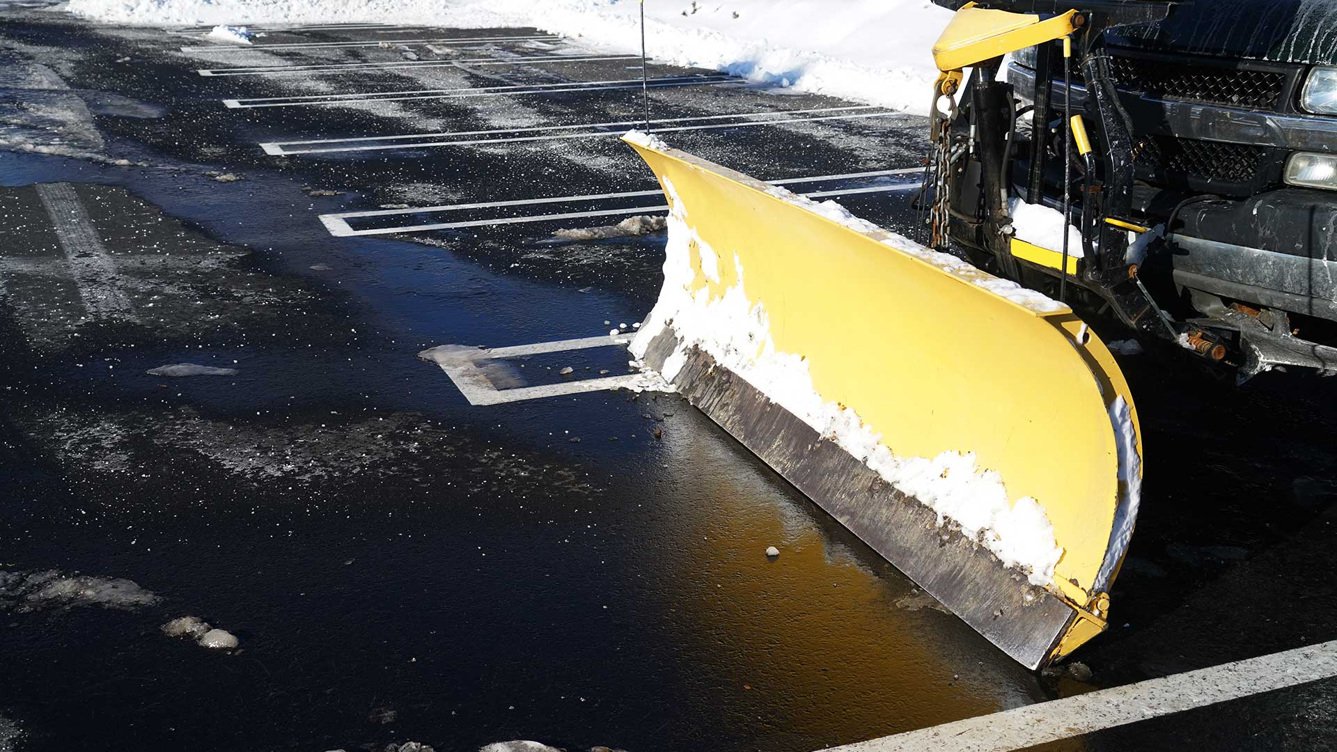 Snow plowing truck in a parking lot clear of snow and coated with salt to melt the ice.