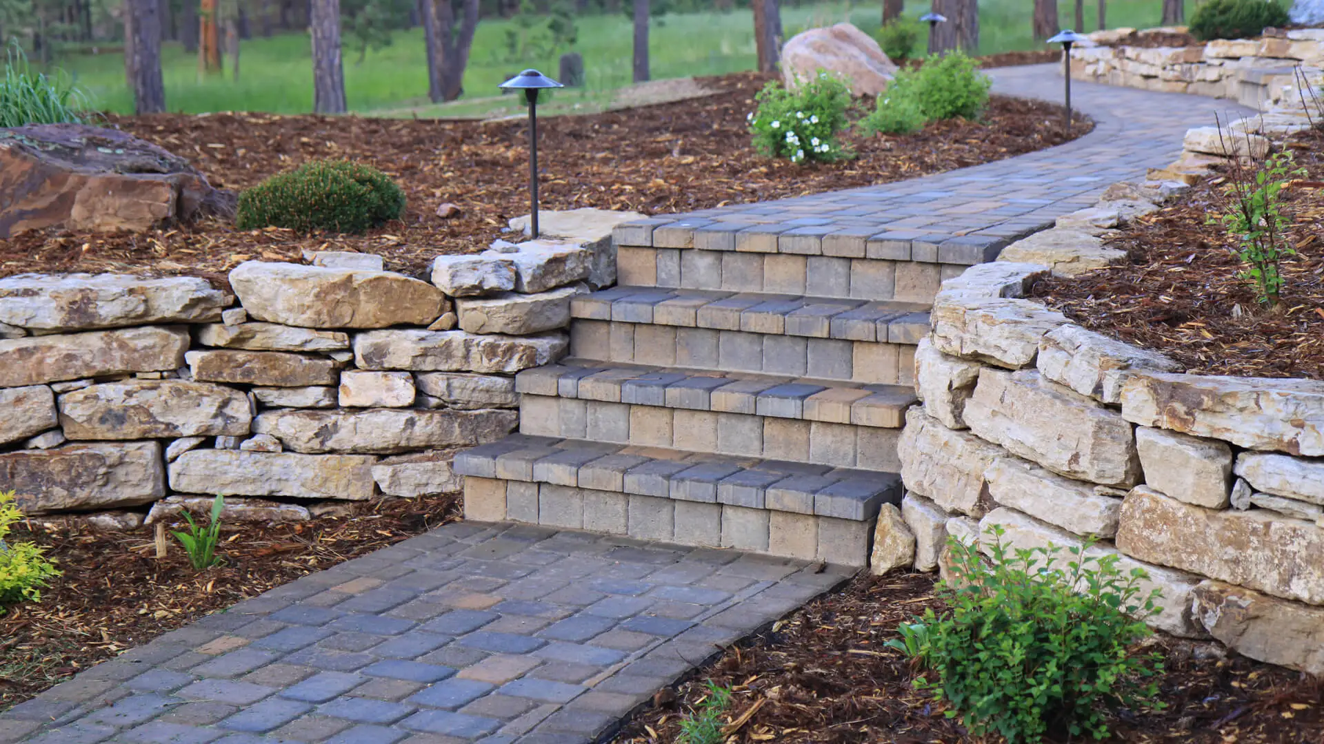 Gorgeous back yard patio at the base of a deck made with flagstones and rock in Matthews, NC and surrounding areas.