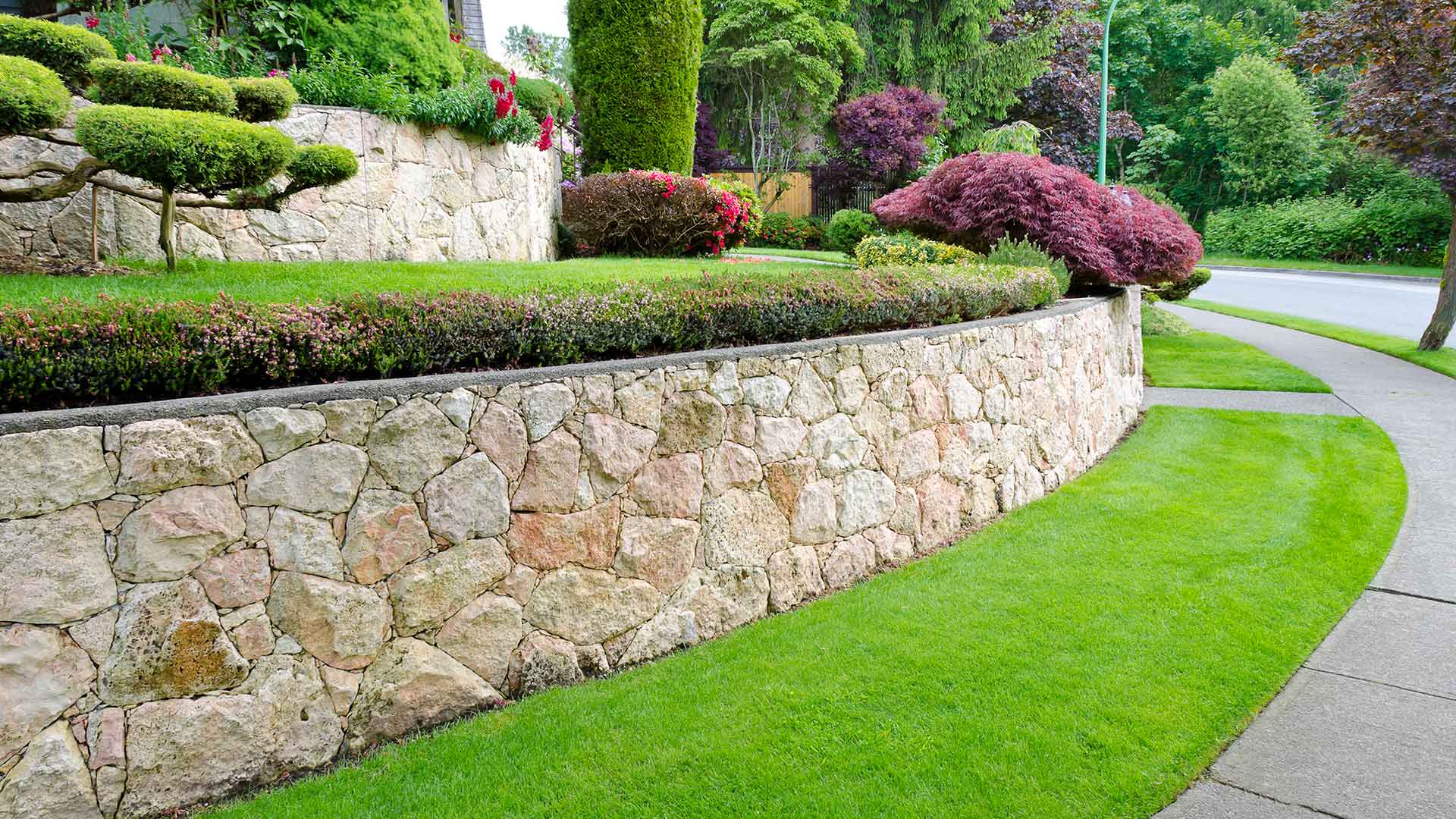 Gorgeous retaining wall with landscape bed and healthy grass.