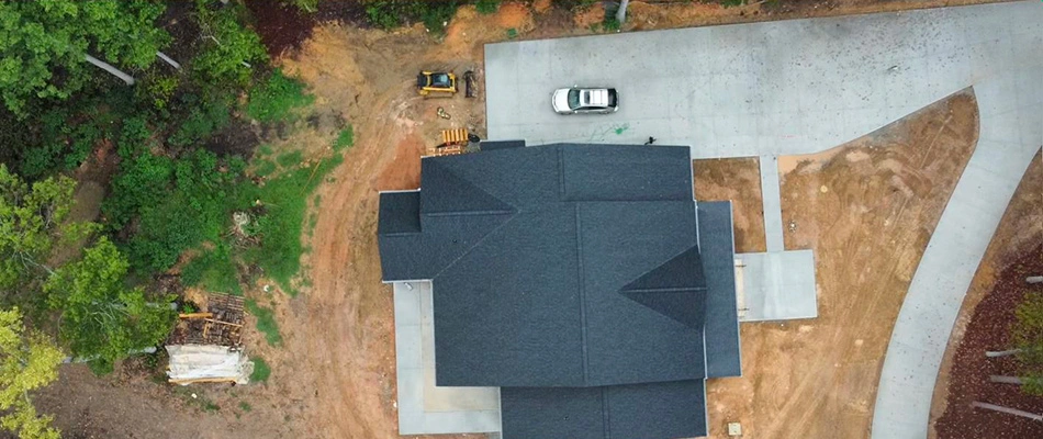 Beautiful home surrounded by trees with Carolina Turf workers installing a new lawn.