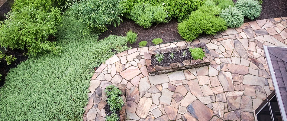 Flagstone patio with bushes and plants in the backyard of a nice house in Charlotte, NC.