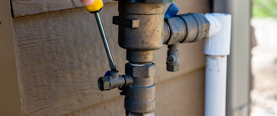 A sprinkler irrigation system's backflow prevention system being adjusted.