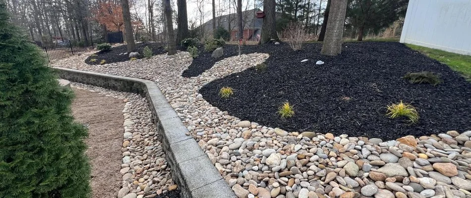 Landscape area in Matthews, NC, with rocks, black mulch, and trees.