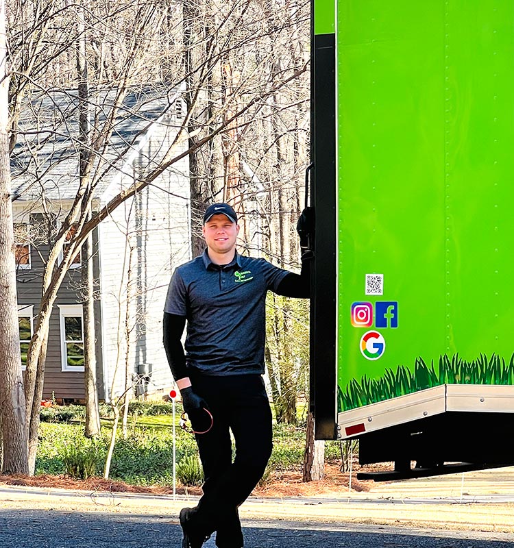 Professional lawn care expert standing next to a company truck near Midland, NC.