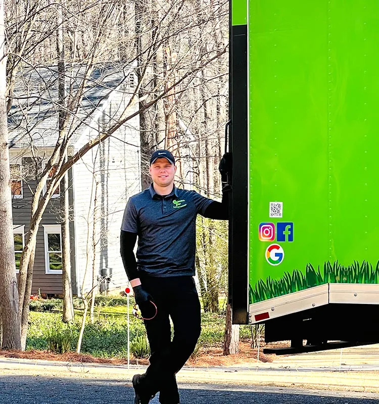 Professional lawn care expert standing next to a company truck near Midland, NC.