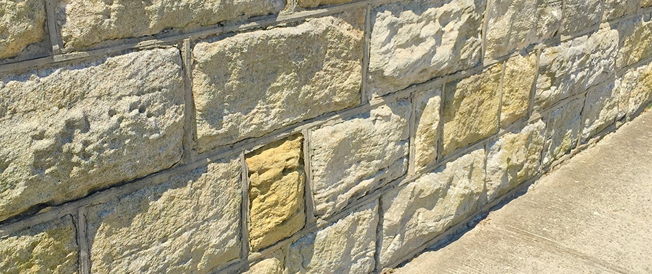 A stone and mortar retaining wall by a sidewalk in Matthews, NC.