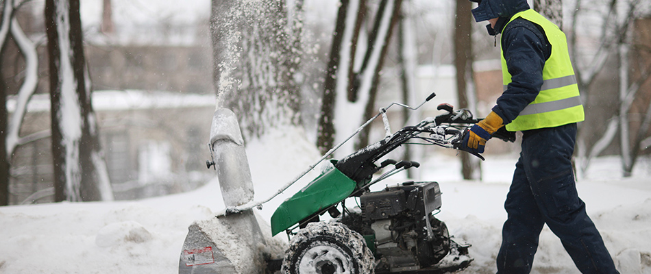Man pushing snow blower and clearing a side walk covered in snow near Mathews, NC.