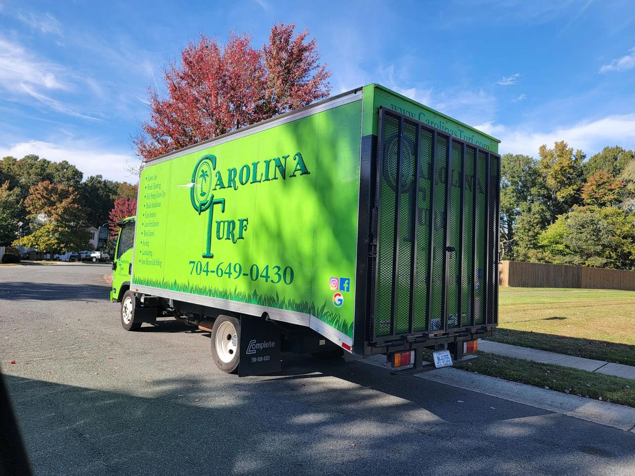 The Carolina Turf Lawn and Landscape team with their uniforms on, company trucks behind them, and the setting sun to the right.